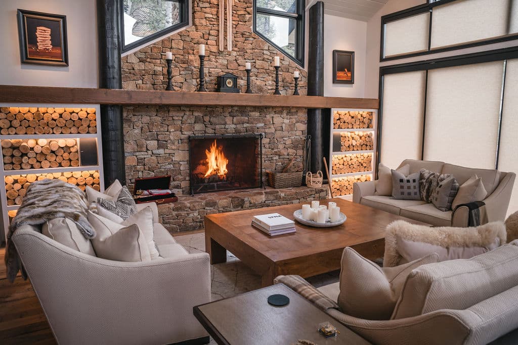 A stone fireplace lit in a mountain living room, the house ready for arrival
