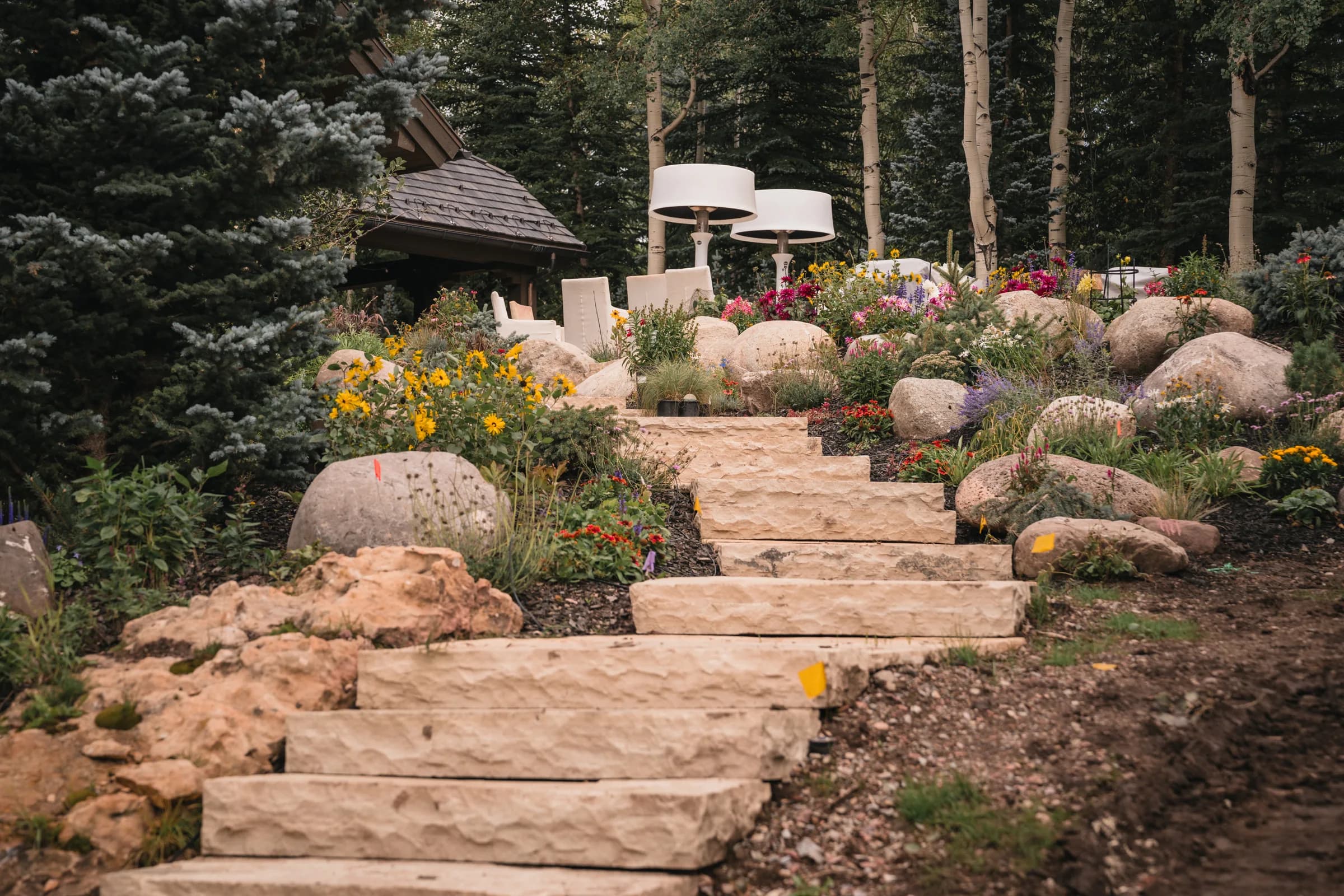 Stone steps lead through flowering garden beds and boulders.